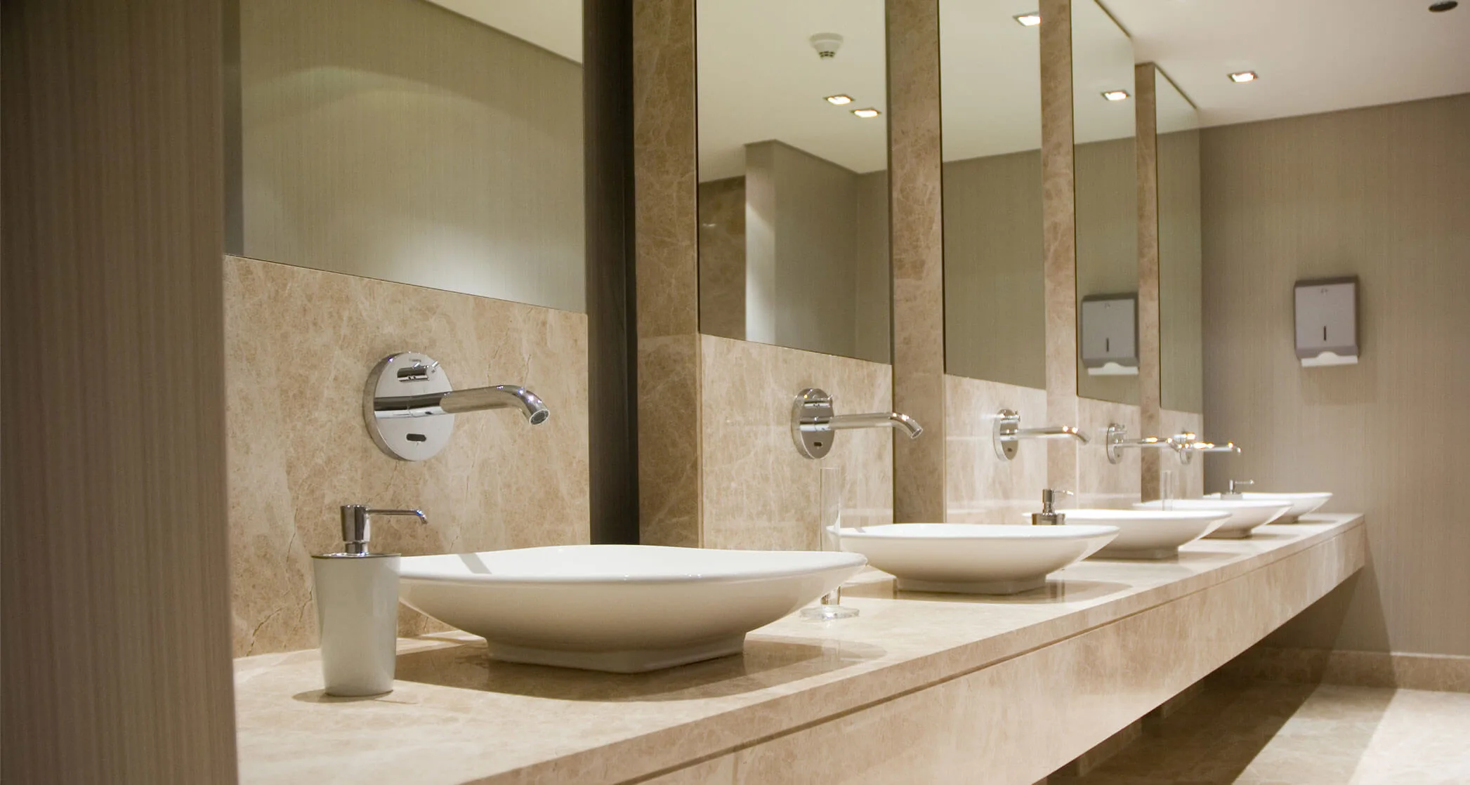Salle de toilettes commerciale propre avec une rangée de lavabos